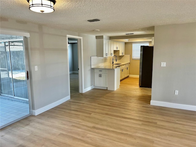 kitchen featuring visible vents, freestanding refrigerator, light countertops, light wood-style floors, and a sink