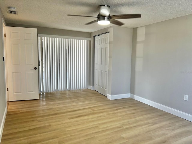 spare room with a ceiling fan, light wood-style flooring, baseboards, and a textured ceiling