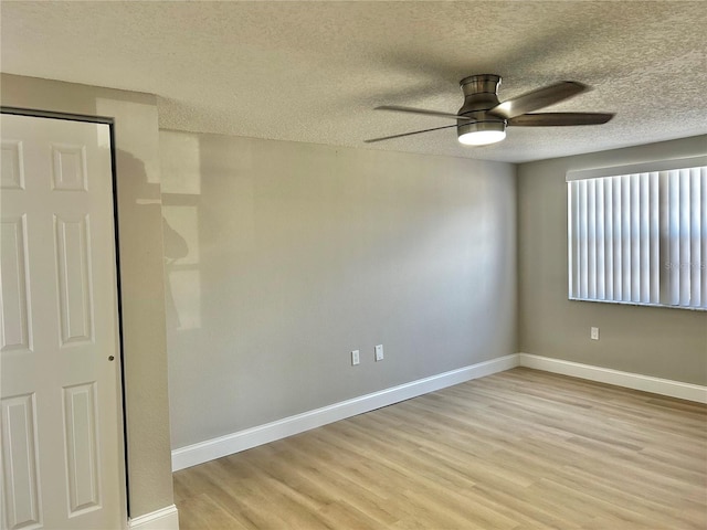 empty room with baseboards, ceiling fan, a textured ceiling, and light wood finished floors