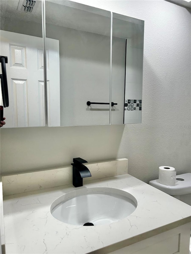 bathroom featuring a textured wall and vanity