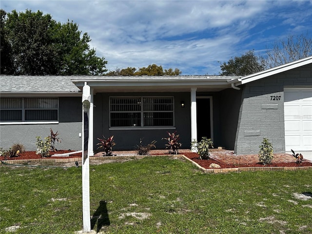 doorway to property with a garage and a yard