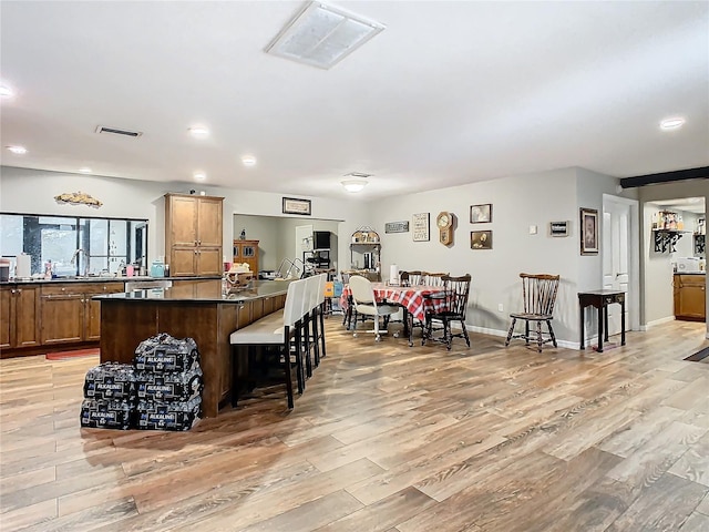 kitchen with sink, a kitchen bar, and light hardwood / wood-style flooring