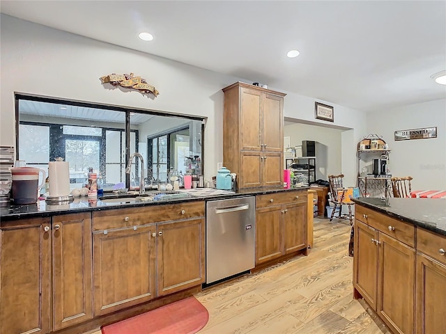 kitchen featuring sink, dark stone countertops, dishwasher, and light wood-type flooring