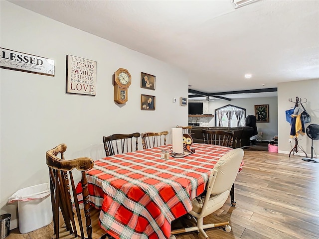 dining room with a fireplace, light hardwood / wood-style flooring, and ceiling fan