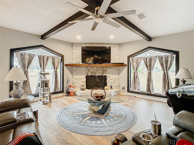 living room featuring a fireplace, vaulted ceiling with beams, ceiling fan, and light wood-type flooring