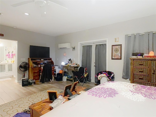 bedroom with ceiling fan, light hardwood / wood-style floors, ensuite bath, and a wall unit AC