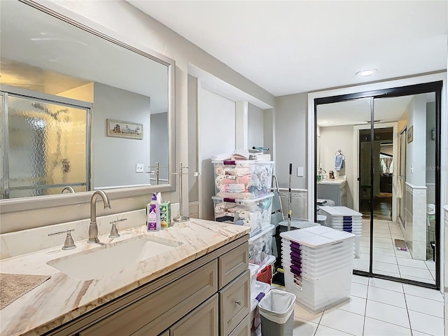 bathroom featuring vanity, a shower with shower door, and tile patterned flooring