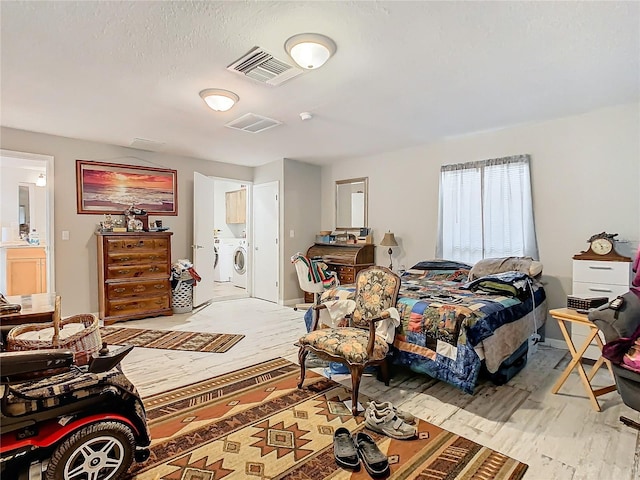 bedroom with washing machine and dryer and connected bathroom