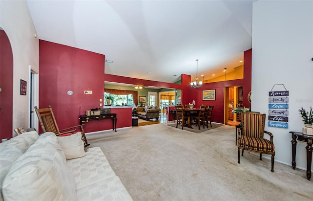 carpeted living room with a notable chandelier and high vaulted ceiling