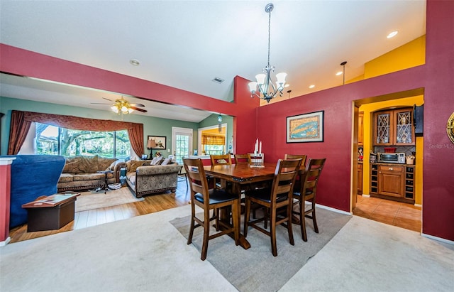 dining space with light carpet, ceiling fan with notable chandelier, and vaulted ceiling