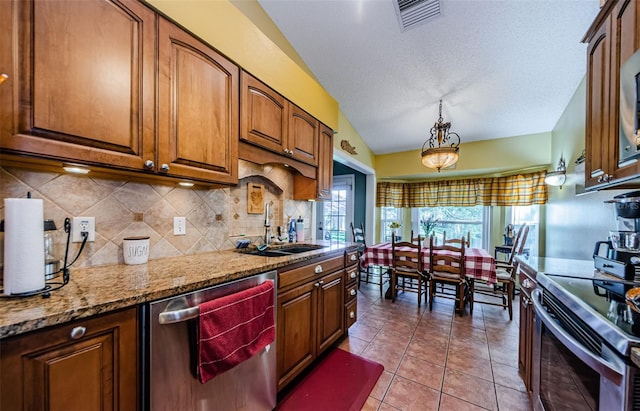 kitchen with light tile patterned flooring, sink, decorative light fixtures, appliances with stainless steel finishes, and light stone countertops