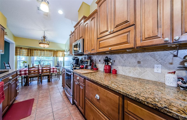 kitchen featuring light tile patterned flooring, pendant lighting, decorative backsplash, light stone counters, and stainless steel appliances