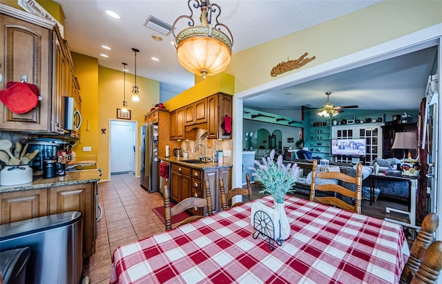 tiled dining room with ceiling fan and sink