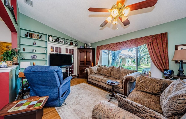 living room with vaulted ceiling, ceiling fan, a textured ceiling, and light hardwood / wood-style flooring