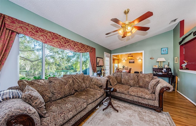 living room featuring vaulted ceiling, hardwood / wood-style floors, ceiling fan, and a textured ceiling