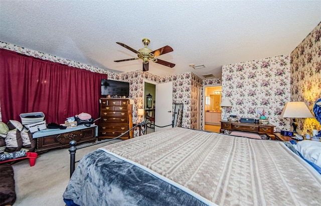 bedroom featuring ensuite bathroom, carpet flooring, a textured ceiling, and ceiling fan