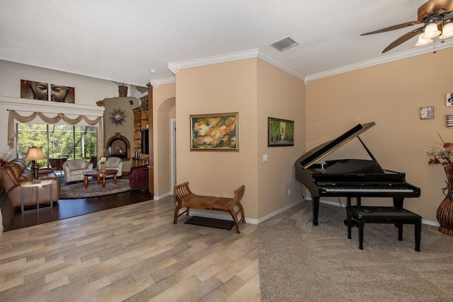 living area featuring ceiling fan, ornamental molding, and light hardwood / wood-style flooring