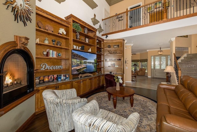 living room featuring dark wood-type flooring, crown molding, and a towering ceiling