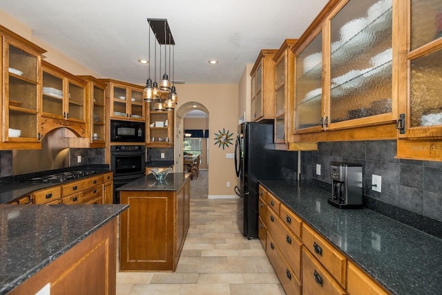 kitchen with decorative backsplash, hanging light fixtures, black appliances, and dark stone countertops