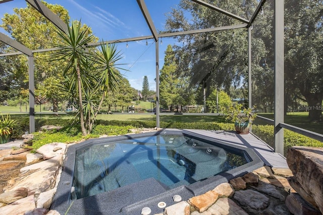 view of swimming pool with glass enclosure, a jacuzzi, and a lawn