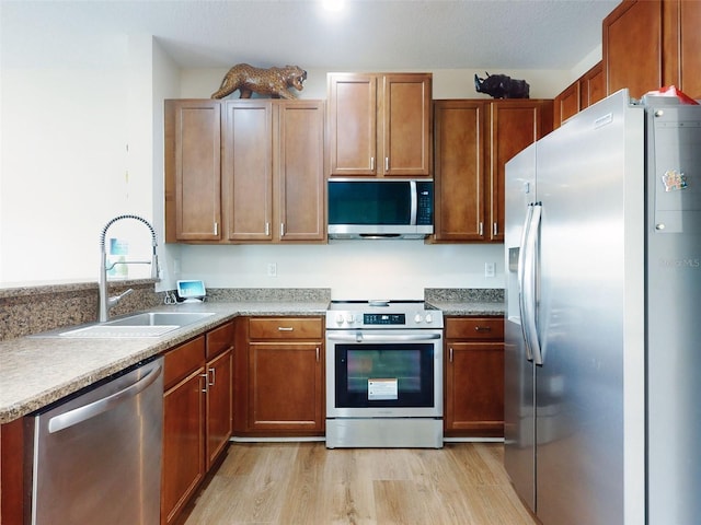 kitchen with stainless steel appliances, sink, and light hardwood / wood-style flooring