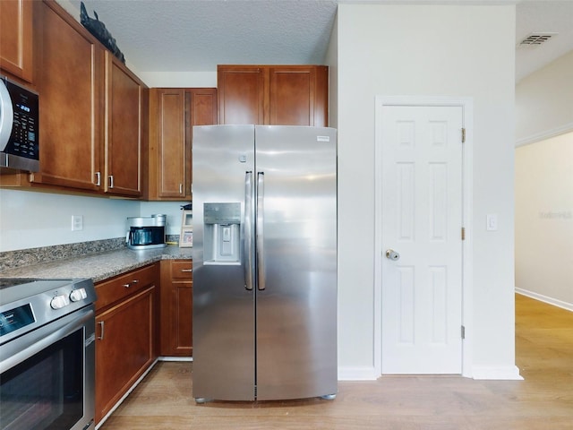 kitchen with appliances with stainless steel finishes and light hardwood / wood-style flooring