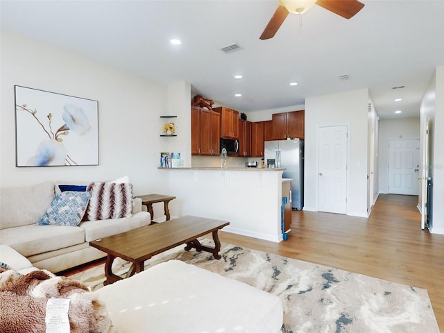 living room featuring ceiling fan and light hardwood / wood-style flooring