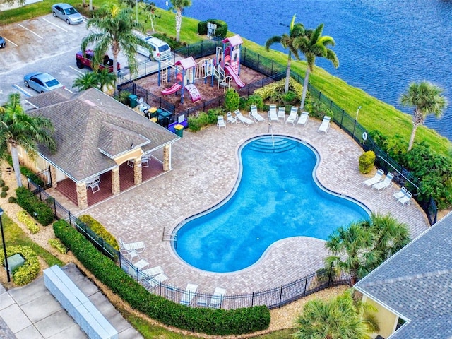 view of pool featuring a patio, a playground, and a water view