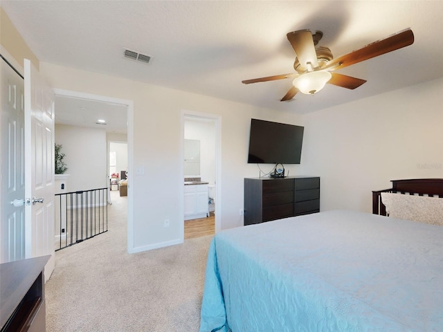 bedroom featuring light colored carpet, ceiling fan, and ensuite bathroom