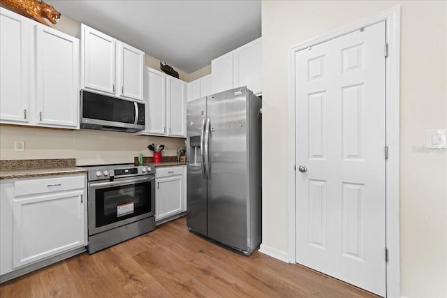 2775 Revolution St Unit 103, Melbourne, FL 32935 - kitchen featuring white cabinetry, stainless steel appliances, dark countertops, and light wood finished floors