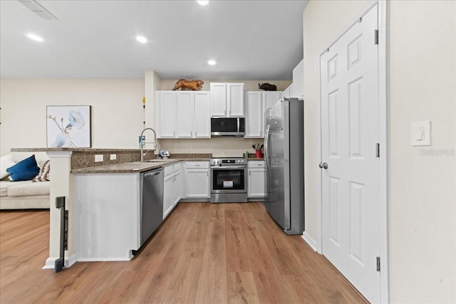 2775 Revolution St Unit 103, Melbourne, FL 32935 - kitchen with a peninsula, appliances with stainless steel finishes, light wood finished floors, and a sink