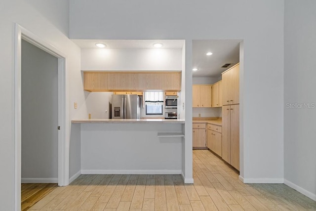 kitchen with light wood-type flooring, kitchen peninsula, light brown cabinetry, and appliances with stainless steel finishes