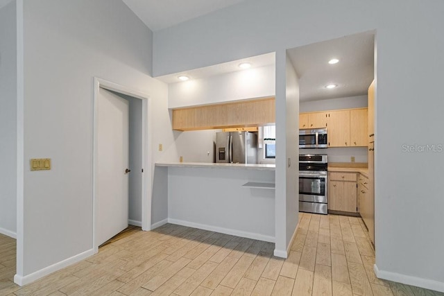 kitchen with kitchen peninsula, light brown cabinets, light wood-type flooring, a high ceiling, and stainless steel appliances