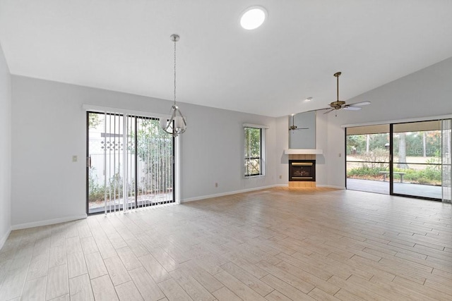 unfurnished living room featuring ceiling fan, light hardwood / wood-style flooring, a tile fireplace, and vaulted ceiling