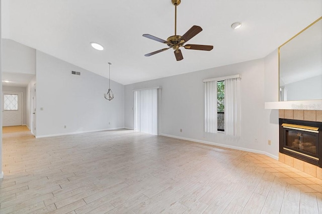 unfurnished living room with light wood-type flooring, vaulted ceiling, ceiling fan, and a tile fireplace