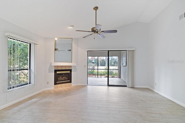 unfurnished living room with a tiled fireplace, light wood-type flooring, vaulted ceiling, and ceiling fan