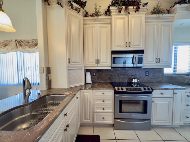 kitchen with sink, decorative backsplash, light tile patterned floors, and appliances with stainless steel finishes