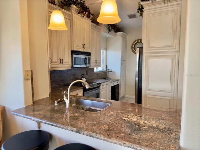 kitchen featuring backsplash, appliances with stainless steel finishes, kitchen peninsula, and dark stone countertops