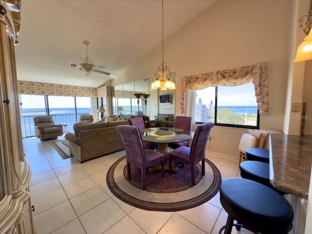 dining space featuring vaulted ceiling, ceiling fan with notable chandelier, and light tile patterned floors