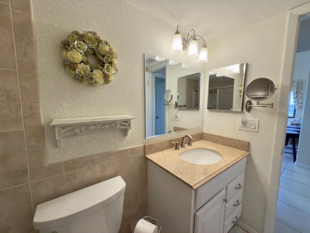 bathroom with vanity, toilet, and tile walls