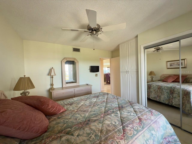 bedroom with ceiling fan, a textured ceiling, light tile patterned floors, and a closet