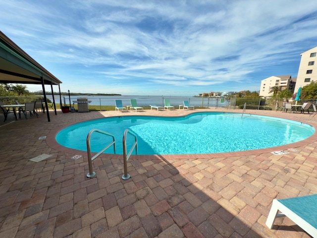 view of pool featuring a water view and a patio