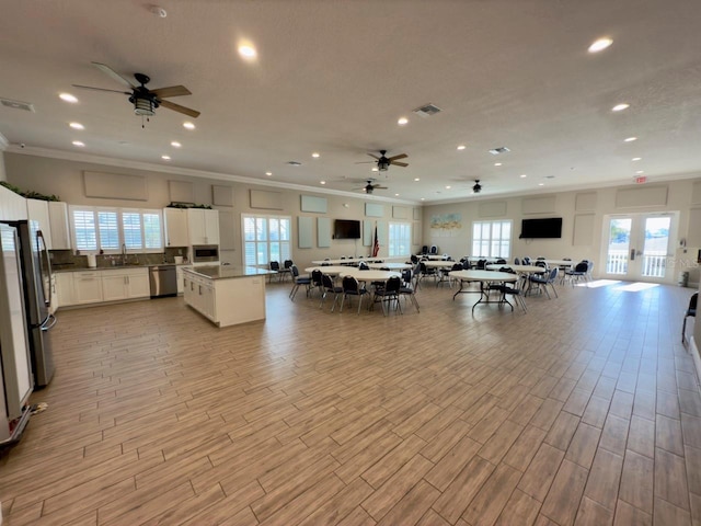 dining space featuring sink, ceiling fan, light hardwood / wood-style flooring, and ornamental molding