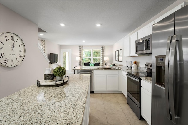 kitchen with sink, white cabinetry, light stone countertops, stainless steel appliances, and light tile patterned floors