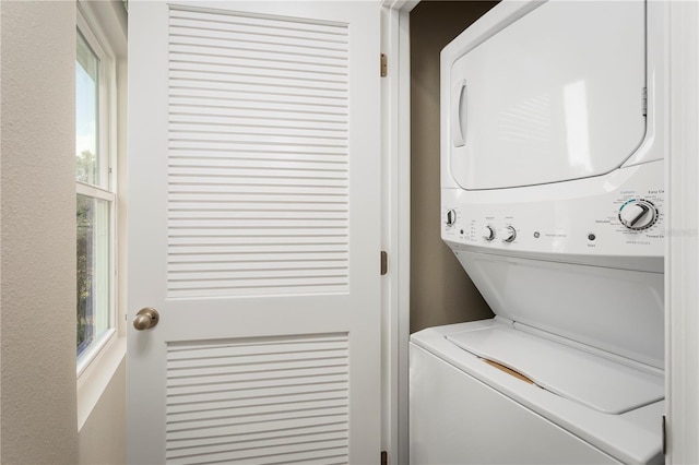 laundry area with plenty of natural light and stacked washer / dryer