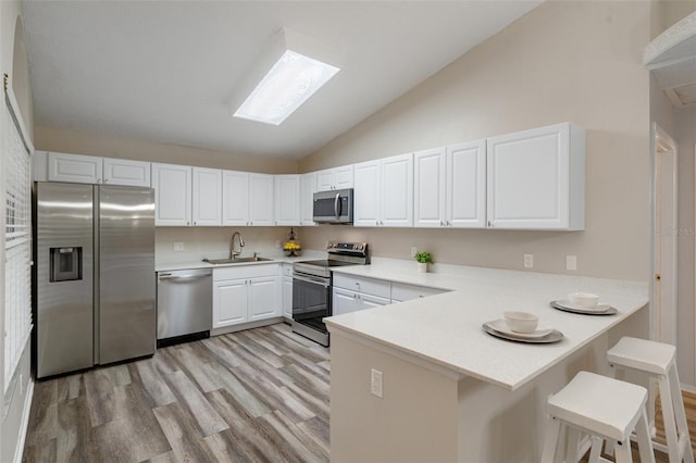 kitchen with a kitchen breakfast bar, white cabinetry, appliances with stainless steel finishes, and kitchen peninsula