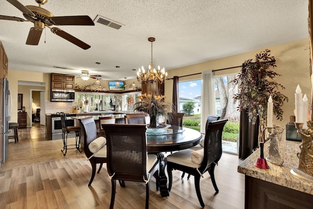 dining area featuring light hardwood / wood-style floors, a textured ceiling, and a notable chandelier