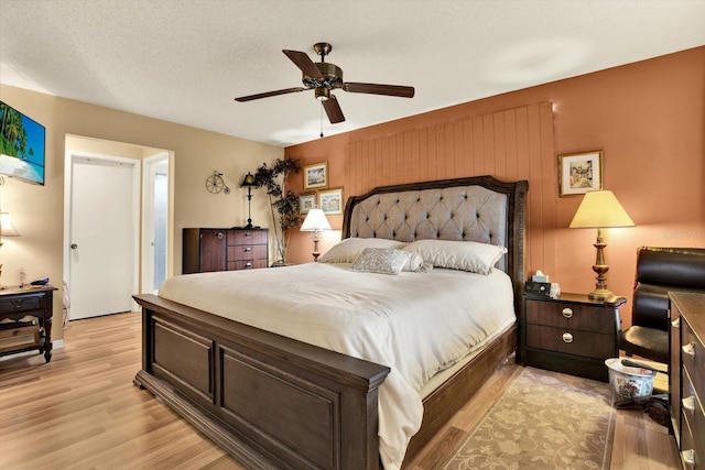 bedroom with light wood-type flooring, a textured ceiling, and ceiling fan