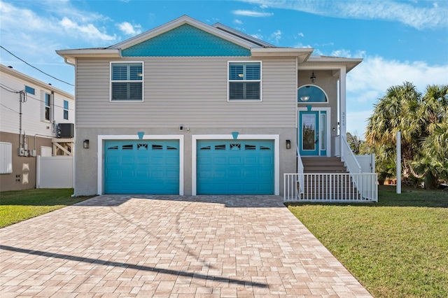 view of front of house featuring central AC, a garage, and a front lawn