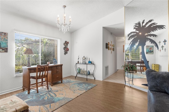 office featuring a notable chandelier, vaulted ceiling, a textured ceiling, and light wood-type flooring